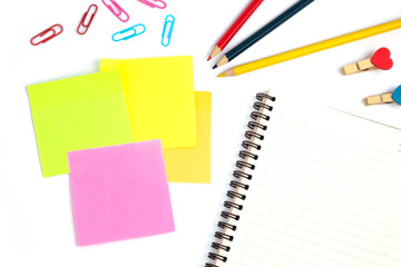 color pencils and notebooks, sticky note, paper clip in many colors and clothespins placed on a white background in the home studio. This concept is used as an illustration for education idea