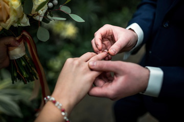 bridegroom puts a wedding ring on bride’s finger
