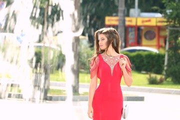 A beautiful young girl poses in an elegant red dress at her prom 