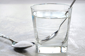 Salt water in a glass cup and salt in a teaspoon. Salt water has high level of minerals and salt...