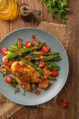 Roasted chicken breast, served on asparagus with tomato sauce, dried tomatoes. Top view.