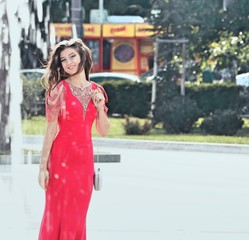 Fototapeta premium A beautiful young girl poses in an elegant red dress at her prom 