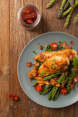 Roasted chicken breast, served on asparagus with tomato sauce, dried tomatoes. Top view.