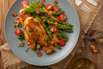 Roasted chicken breast, served on asparagus with tomato sauce, dried tomatoes. Top view.