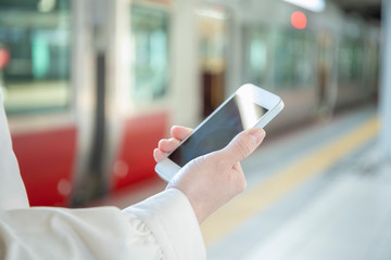 駅のホームでスマートフォンを触る女性の手元