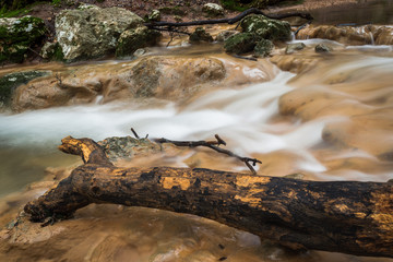 Rapid river running through the stones in an amazing green mediterranean mountain forest long exposure