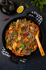 Wheat noodles with black sesame, fried in a wok with chicken and vegetables. Top view.