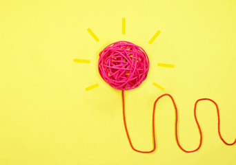 Concept of Ideas and Innovation. Light bulb concept of red string ball with wired string on yellow...
