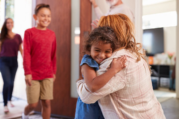 Grandparents Greeting Grandchildren At Front Door As They Comes To Visit