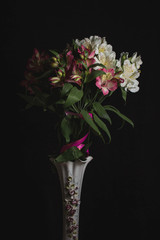 white and lilac flowers in a vase on a black background