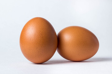 Two eggs on a white background. One egg stands, the other lies