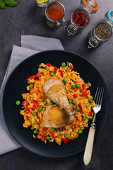 Arroz con pollo. Baked pieces of chicken with bone, rice with paprika and peas.