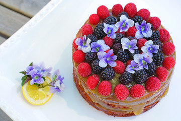 Lemon cake with fresh berries and violet flowers