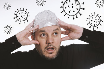 paranoid man wearing tin foil hat as protection against corona virus covid-19 - conspiracy theaory
