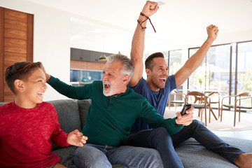 Excited Multi-Generation Male Hispanic Family Celebrating Watching Sports On TV