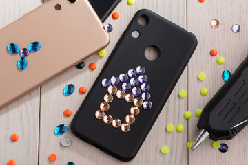 Child attaching rhinestones onto phone cases with a glue gun