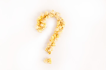 Question mark lined with corn kernels on a white background. Flat top view. Copyspace for text.