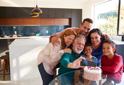 Multi-Generation Hispanic Family Taking Selfie To Celebrate Granddaughters Birthday At Home