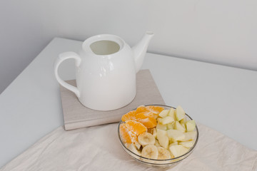 
sliced ​​fruit in a plate and teapot, proper breakfast