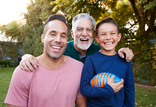 Portrait Of Multi-Generation Male Hispanic Family In Garden Smiling At Camera
