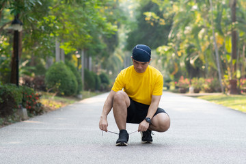 young man runner tying shoelaces on  asphalt  road background