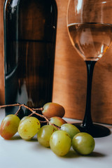 Bottle of wine, glass and grapes on a wooden background