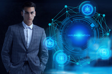Business, Technology, Internet and network concept. Young businessman working on a virtual screen of the future and sees the inscription: Implementation