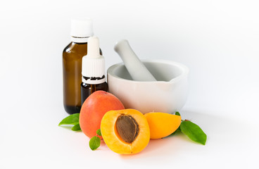 natural cosmetics concept, apricots with glass bottles with oil on, white background