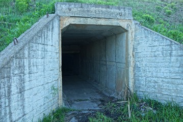 the entrance to the old tunnel of gray concrete in the ground and green grass on the street