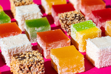 Turkish delight square pieces on a bright pink background close up