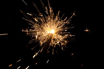 Orange sparkler countdown with spread of golden glitter sparks. Luxury entertainment at e.g. New Years Eve, Independence Day or birthday party celebration. Glowing light spark on dark background