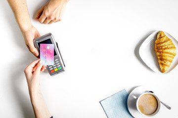 Croissant and coffee payment by card in cafe top view