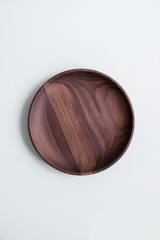 Wooden utensils for food on a white isolated background. Handcrafted natural bowl plates from an expensive variety of wood. Empty round tray. Eco-friendly cookware.