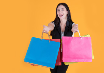 Shopping woman holding shopping bags on yellow background at copy space. Cheerful happy woman enjoying shopping