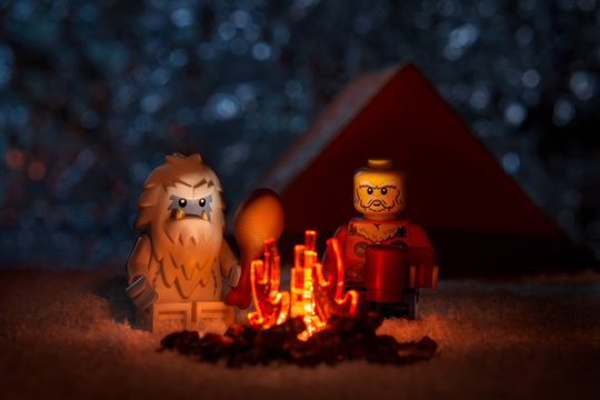 Moscow, Russia - May 5, 2019: Lego-man with Yeti near bonfire on starry sky background, funny concept unreal friendship