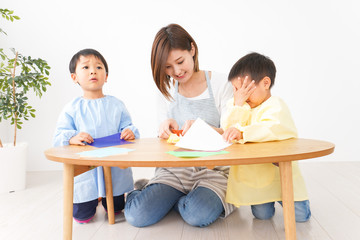 幼稚園で折り紙をする子どもと先生
