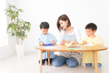 幼稚園で折り紙をする子どもと先生