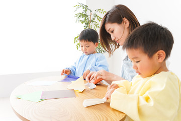 幼稚園で折り紙をする子どもと先生