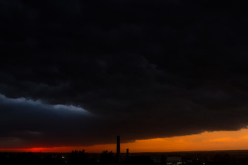Black thunderclouds at sunset. Bright orange sunset and dark clouds. Storm sky