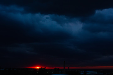 Fototapeta premium Black thunderclouds at sunset. Bright orange sunset and dark clouds. Storm sky
