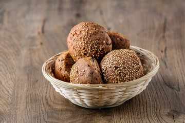 Round buns with sesame seeds in a wicker basket.