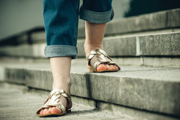 female feet in beige sandals on the steps