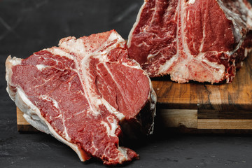 Raw T-bone steak cooking on stone table.