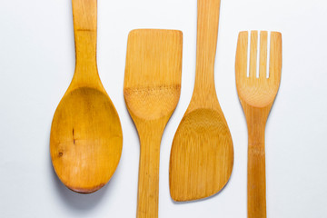 Four wooden cutlery lie on two different sides on a white background. Wooden spoon, wooden fork. And two wooden spatulas