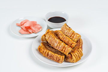 Deep Fried Crispy Streaky Pork Belly Thai and Chinese Food on White Plate with Sauce and Ginger on White Background Isolated.