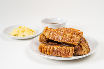 Deep Fried Crispy Streaky Pork Belly Thai and Chinese Food on White Plate with Sauce and Ginger on White Background Isolated.