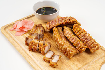 Deep Fried Crispy Streaky Pork Belly Thai and Chinese Food on Cutting Board with Sauce and Ginger on White Background Isolated.