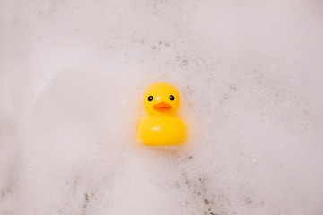 Yellow rubber duck in the bath with bubble foam
