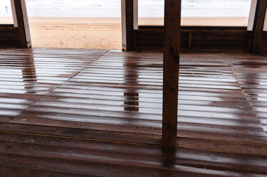 Flooded wooden boardwalk in empty house on rainy day close to the beach with nobody
