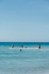 Fototapeta na wymiar families enjoying the beach on a blue day with no clouds